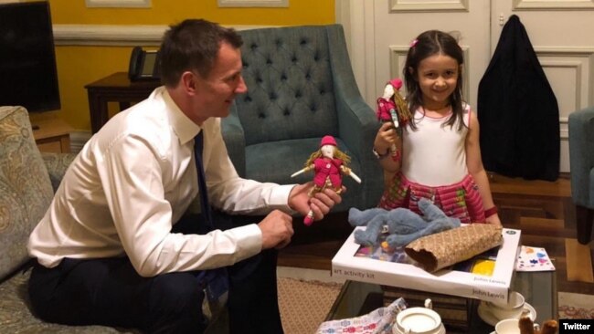 FILE - British Foreign Secretary Jeremy Hunt shares a moment with the daughter of jailed Nazanin Zaghari-Ratcliffe, Gabriella, in a photo shared on Twitter by @FreeNazanin.