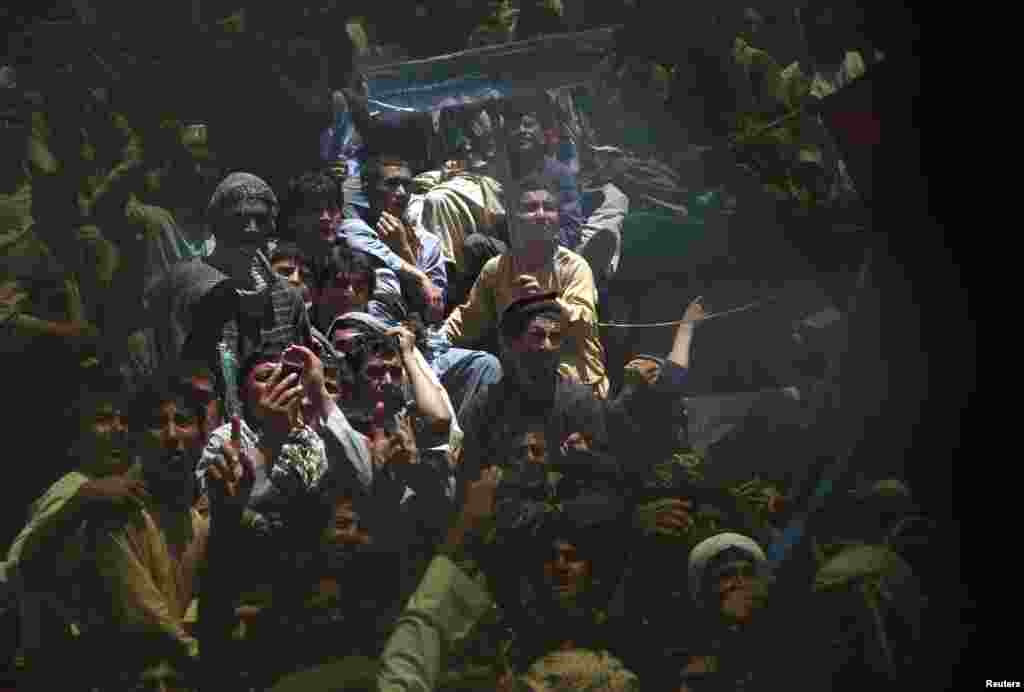 Supporters of Afghan presidential candidate Abdullah Abdullah are seen through a broken window during an election campaign in Qala i Naw, capital of Badghis province.