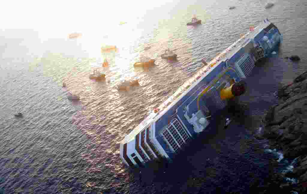 Kapal pesiar Costa Concordia setengah terguling setelah menabrak batu dekat Pulau Giglio, 14 Januari 2012 (Reuters).