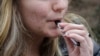 FILE - An unidentified 15-year-old high school student uses a vaping device near the school's campus in Cambridge, Massachusetts, April 11, 2018. 