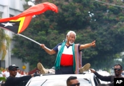 East Timorese independence hero Xanana Gusmao, center, waves a national flag upon arrival in Dili, East Timor, March 11, 2018.