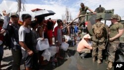 21일 필리핀 재해 복구를 위해 파병된 미 해군들이 타클로반시의 태풍 피해 주민들에게 식수를 나눠주고 있다.