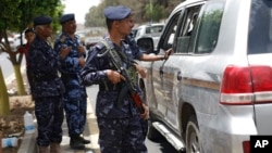 Policemen check a car at a checkpoint on a street leading to the Yemeni Interior Ministry in Sanaa, Yemen, Aug. 23, 2014. 
