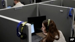 In this Nov. 8, 2017, photo, Jessica McShane, an employee at Interactions Corp., foreground, monitors person-to-computer communications, helping computers understand what a human is saying, in the "intent analysis" room at the company's headquarters in Franklin, Mass. “That information is used to feedback into the system using machine learning to improve our model,” said Robert Nagle, Interactions’ chief technology officer. “Next time through, we’ve got a better chance of being successful.”