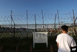 A man walks by the wire fences adorned with national flags near an information sign showing the distance to North Korea's Kaesong city and South Korea's capital, Seoul, at the Imjingak Pavilion in Paju, South Korea, Sept. 15, 2017. North Korea conducted its longest-ever test flight of a ballistic missile Friday, sending an intermediate-range weapon hurtling over U.S. ally Japan into the northern Pacific Ocean.