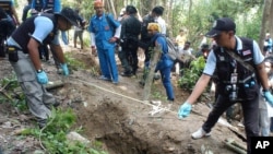 Thai policemen measure shallow graves in Songkhla province in southern Thailand, May 2, 2015.