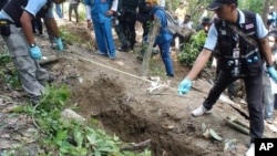 Thai policemen measure shallow graves in Songkhla province in southern Thailand, May 2, 2015.