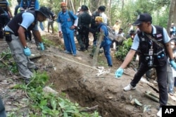 FILE - Thai policemen measure shallow graves in Songkhla province in southern Thailand, May 2, 2015.