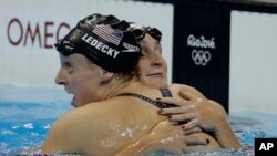 Atlet renang Katie Ledecky (kiri) dipeluk sesama perenang AS Leah Smith setelah meraih medali emas gaya bebas putri 400 meter dan mencatat rekor dunia baru pada Olimpiade Rio (7/8). (AP/Matt Slocum)