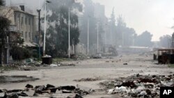 FILE - In this photo released by the Syrian official news agency SANA, damaged and blocked street where clashes erupted between the Syrian government forces and rebels, near the Abbassiyin square, east Damascus, Syria, March 20, 2017. 