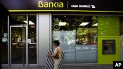 woman walks by an ATM cash machine at a branch of the Bankia bank in Madrid, June 6, 2012.