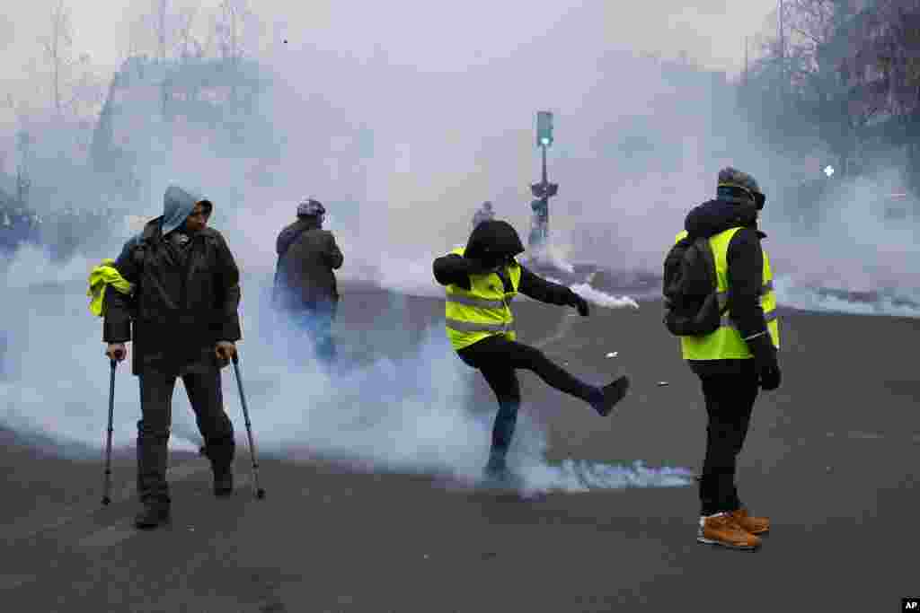 یکی از معترضان فرانسوی در جریان تظاهرات جلیقه زردها در پاریس گلوله گاز اشک آور را از خود دور می&zwnj;کند.