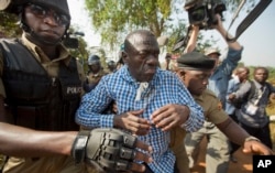 Uganda's main opposition leader Kizza Besigye, center, is arrested by police and thrown into the back of a blacked-out police van which whisked him away and was later seen at a rural police station, outside his home in Kasangati, Uganda, Feb. 22, 2016.