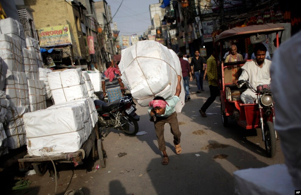 An Indian labourer carries a load through a busy street on a hot afternoon in New Delhi, India.
