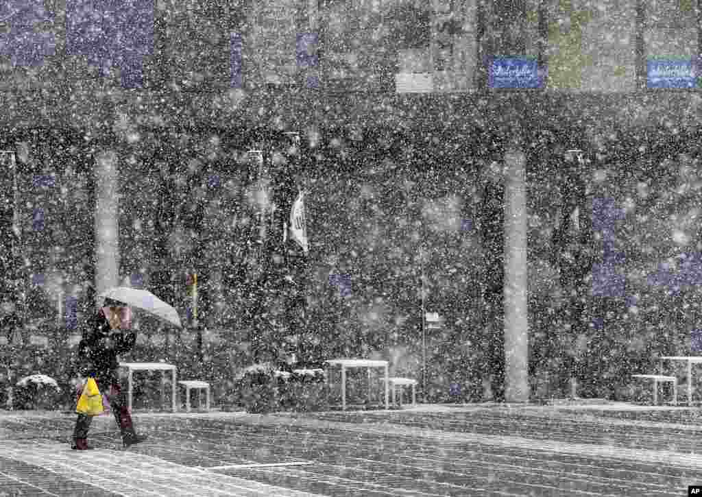 Seorang perempuan menyeberangi lapangan saat hujan salju lebat melanda Frankfurt, Jerman.
