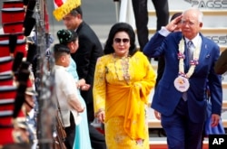 FILE - Najib Razak, right, salutes the troops as he arrives with his wife, Rosmah Mansor, at Clark International Airport in Clark, Pampanga province, north of Manila, Philippines, Nov. 12, 2017.