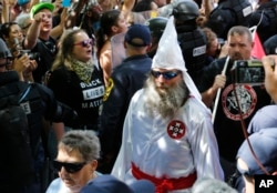 FILE - A KKK white supremacist is escorted by police during a KKK and counter-rally in Charlottesville, Virginia, July 8, 2017.