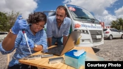 Jaqueline Goes de Jesus (Fundacao Oswaldo Cruz, Salvador), left, and Nuno Faria (University of Oxford, UK) use the Oxford Nanopore MinION device in front of the minibus equipped with a lab, in Joao Pessoa, Brazil. (Courtesy - Ricardo Funari)