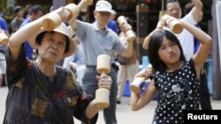A girl exercises with other people using wooden dumbbells during a health promotion event to mark Japan's "Respect for the Aged Day" at a temple in Tokyo on September 17, 2012.