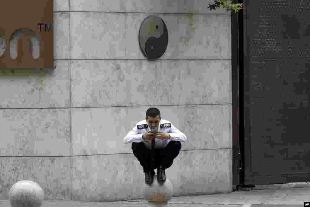 مامور گارد امنیتی در پایتخت چین، در حال چک کردن گوشی خود.&nbsp;