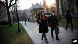 FILE - Yale University sophomore Yupei Guo, left, walks with friend Joseph Lachman on the school's campus in New Haven, Conn., In Nov. 20, 2014. With more undergraduates coming from overseas than ever, some Ivy League universities are reaching out in new 