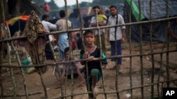 A Rohingya child, newly arrived from Myanmar on the Bangladesh side of the border, stands by a wooden fence at Kutupalong refugee camp in Ukhia, Sept. 5, 2017.