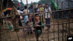 A Rohingya child, newly arrived from Myanmar on the Bangladesh side of the border, stands by a wooden fence at Kutupalong refugee camp in Ukhia, Sept. 5, 2017.