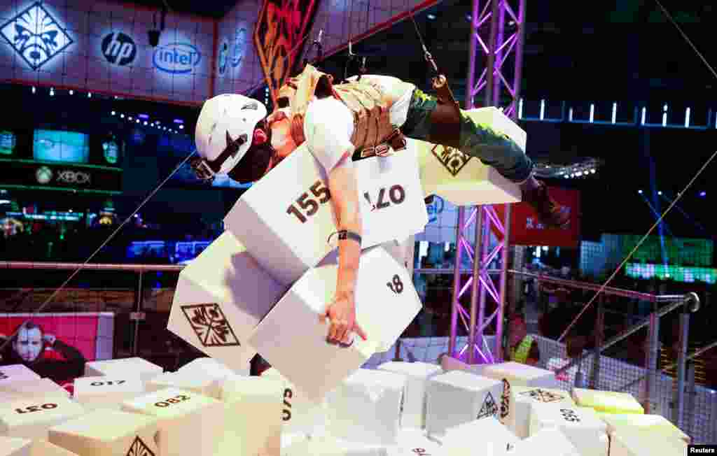 A blind-folded gamer collects as many foam objects as possible as he hangs from the ceiling on the first day of Europe&#39;s digital games fair, Gamescom, in Cologne, Germany.