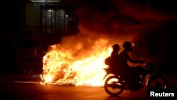 Una motocileta pasa frente a una fogata durante una protesta contra el alza de pasajes en el transporte, en Rio de Janeiro, Brasil.