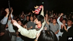 资料照片：在北约误炸中国驻南斯拉夫大使馆之后，北京学生在美国使馆外面焚烧美国国旗。(1999年5月8日)