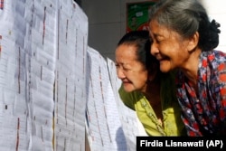 Perempuan lanjut usia mengecek daftar nama caleg di TPS di Bali, Rabu 9 April 2014. (Foto: AP/Firdia Lisnawati)