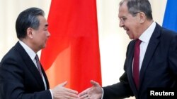 FILE - Russian Foreign Minister Sergey Lavrov shakes hands with Chinese Foreign Minister Wang Yi after their joint news conference following talks in Sochi, Russia, May 13, 2019. 