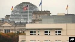 FILE - The American flag flies on top of the U.S. Embassy in front of the Reichstag building that houses the German parliament in Berlin.