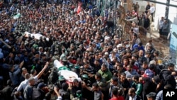 Palestinian mourners carry the bodies of two of the seven Hamas militants who were killed in an Israeli raid late Sunday, during their funerals in Khan Younis, southern Gaza Strip, Nov. 12, 2018.