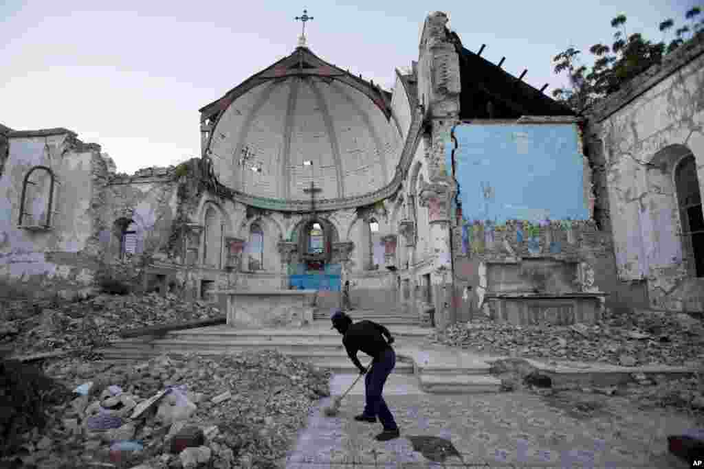 A man sweeps an exposed tiled area of the earthquake-damaged Santa Ana Catholic church, where he now lives, in Port-au-Prince, Haiti.