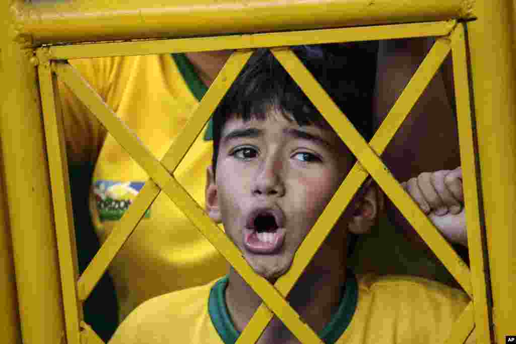 A young soccer fan shouts from outside the stadium fence asking to enter Brazil's soccer team training session in Fortaleza, Brazil, July 3, 2014.