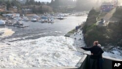 Aux États-Unis, les résidents de l'Oregon regardent une marée haute se précipiter et inonder des parties du port de Depoe Bay, en Oregon, pendant une marée extrêmement haute qui a coïncidé avec une grosse tempête hivernale, le 11 janvier 2020 (AP Photo / Gillian Flaccus)