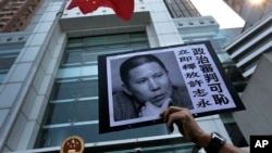 A placard with a photo of legal scholar Xu Zhiyong is raised by a demonstrator protesting against a Chinese court’s decision to sentence him in prison outside the Chinese liaison office in Hong Kong, Jan. 27, 2014.