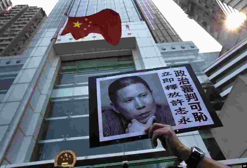 A placard with a photo of legal scholar Xu Zhiyong is raised by a demonstrator protesting against a Chinese court&rsquo;s decision to sentence him to prison, outside the Chinese liaison office in Hong Kong. Xu was sentenced Sunday to four years in prison on the charge of disturbing order in public places.