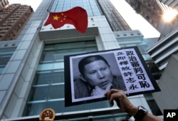 FILE - A placard with a photo of Xu Zhiyong is raised by a demonstrator protesting against a Chinese court’s decision to sentence him in prison outside the Chinese liaison office in Hong Kong, Jan. 27, 2014.