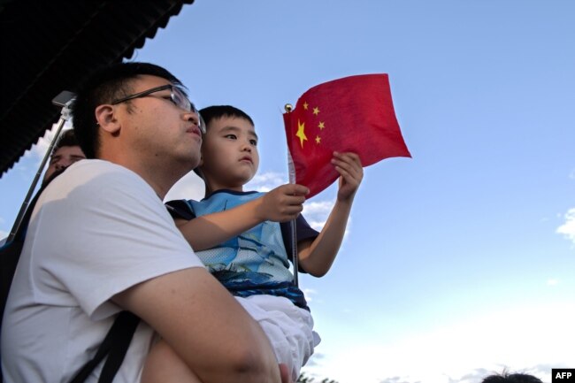 Foto yang diambil pada 6 September 2018 menunjukkan seorang pria menggendong anaknya di sebuah taman di Beijing. China bersiap untuk menghapus kebijakan dua anaknya.