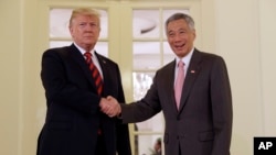 صدر ٹرمپ ، شمالی کوریا کے سربراہ کم جونگ ان سے ملاقات سے قبل سنگاپور کے وزیر اعظم لی لونگ سے مصافحہ کر رہے ہیں۔ 11 جون 2018