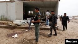 Iraqi policemen inspect the site of a suicide attack at Imam al-Kadhim University in northern Baghdad April 20, 2014.