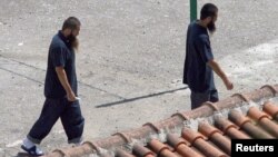 FILE - Two Chinese Uighurs, released from Guantanamo in 2006, are seen following their arrival at a resettlement center in Tirana, Albania.