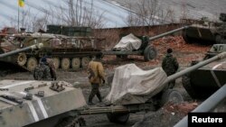 Ukrainian servicemen walk past armored personnel carriers, military vehicles and cannons at their new position as they pull back from the Horlivka region, near Druzhkivka, eastern Ukraine, Feb. 28, 2015. 