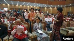 Myanmar's Aung San Suu Kyi smiles as she arrives to give a speech during talks between the government, army and representatives of ethnic armed groups over a ceasefire to end insurgencies, in Naypyitaw, Jan. 12, 2016.