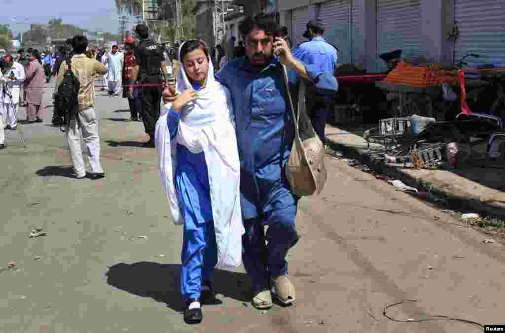 پشاور میں ایک اسکول کے نزدیک بم دھماکے کے بعد ایک شخص طالبہ کو محفوظ جگہ پر لے جا رہا ہے