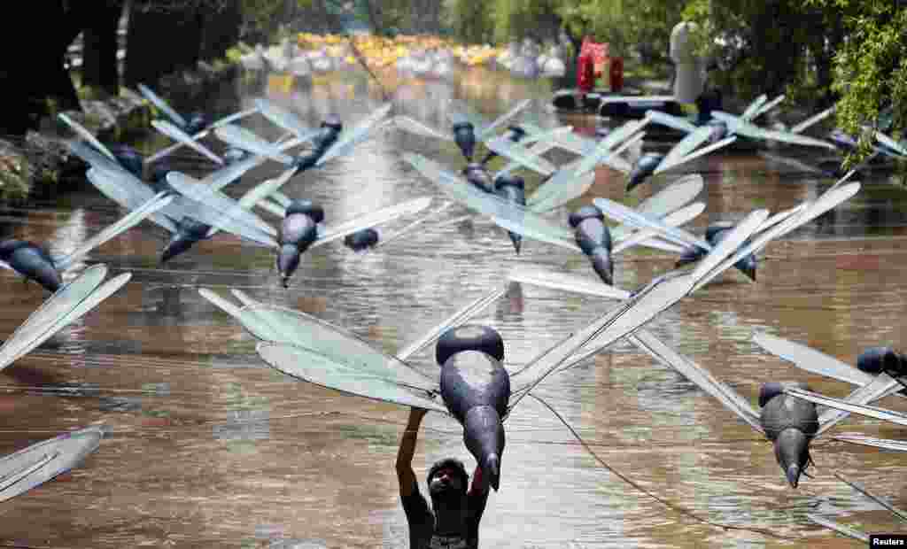 A man adjusts a model of a dragonfly installation over a canal in Lahore, Pakistan.