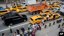 FILE - Passengers board yellow cabs as others wait in line at a taxi stand on 42nd Street outside Grand Central Terminal in New York, Aug. 1, 2018.