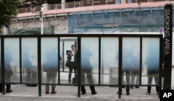 FILE - People gather at a smoking area in Tokyo, April 7, 2017.